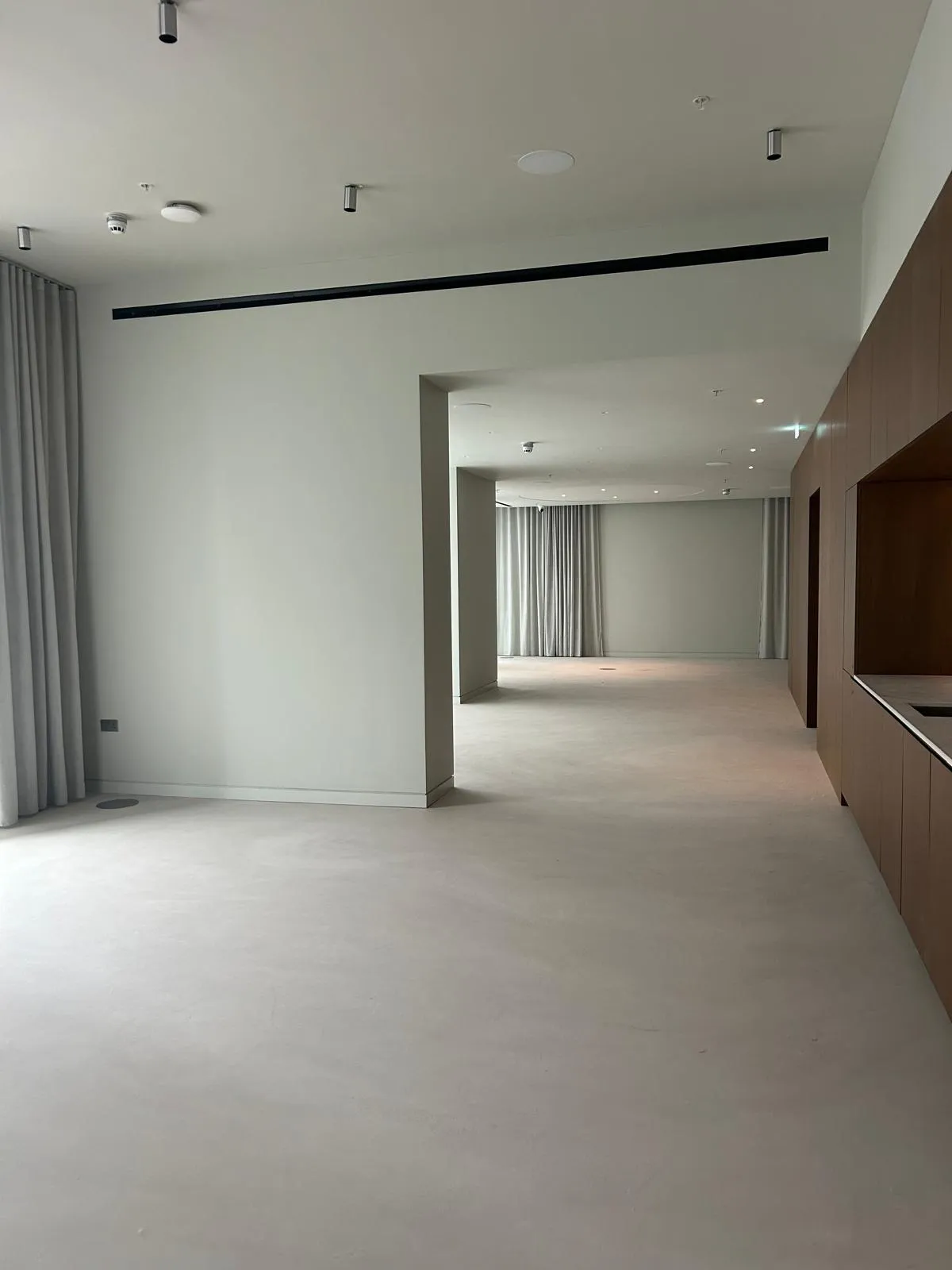 A finished modern commercial interior with warm grey walls, pale flooring and dark timber joinery